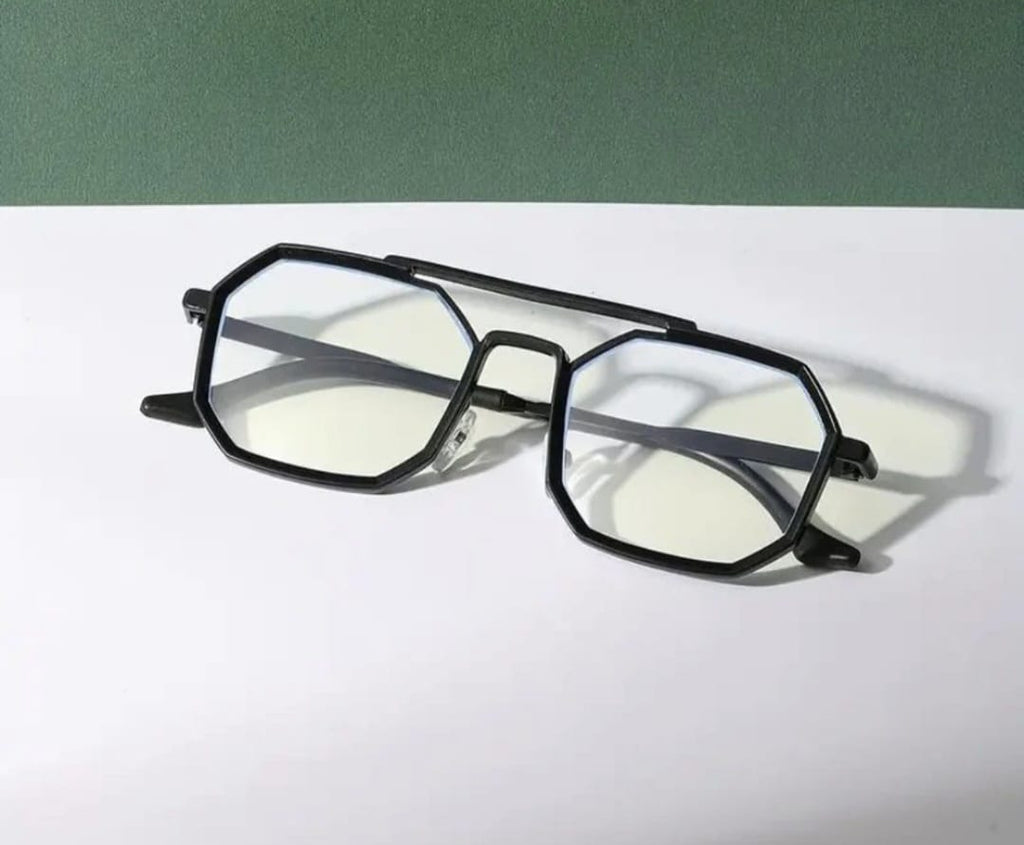Black eyeglasses on a white surface with a green background