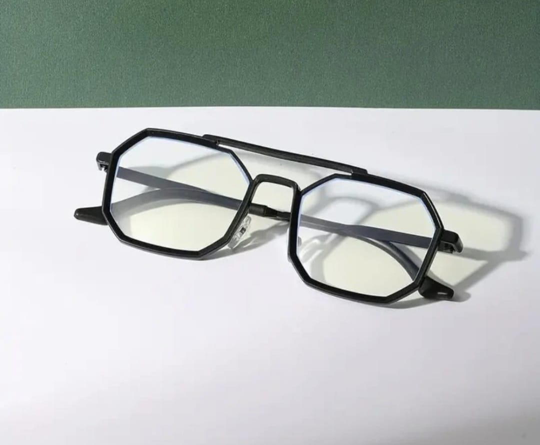 Black eyeglasses on a white surface with a green background